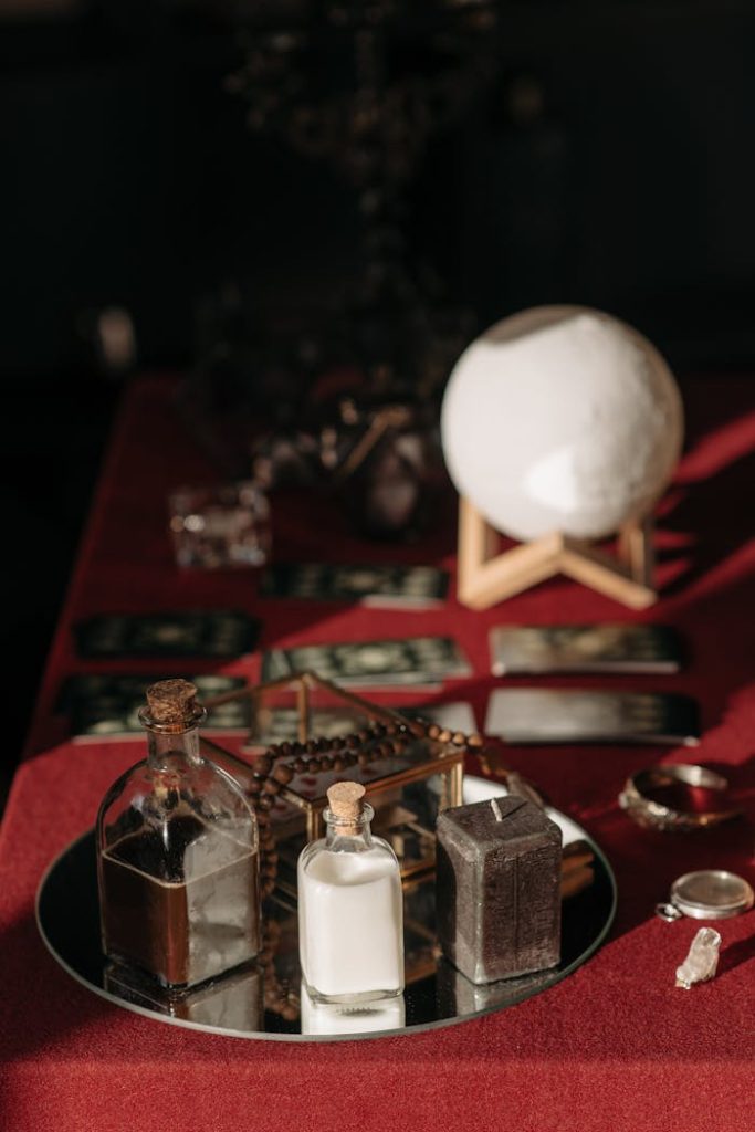An enchanting fortune telling set with tarot cards, crystal ball, and mystical objects on a red cloth.